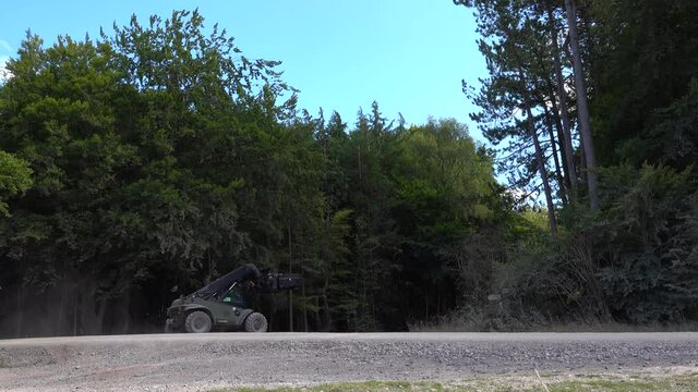 British army JCB fork lift driving though woodland on a military exercise, Wiltshire UK