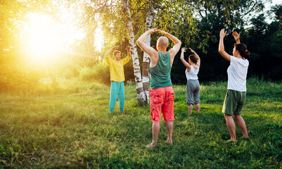 Trainer shows how to do chi gong exercise. Group learning qigong in nature.