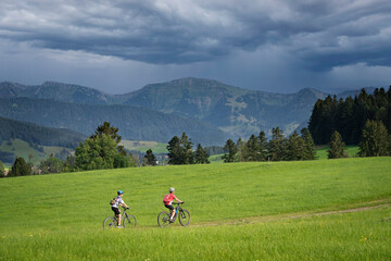 nice and remained young grandmother and her grandson riding their electrc mountain bikes in the Allgaeu Alps near Oberstaufen in Bavaria, Germany