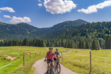 nice and remained young grandmother and her grandson riding their electrc mountain bikes in the...
