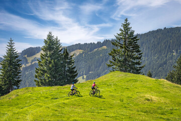 Fototapeta na wymiar nice and remained young grandmother and her grandson riding their electrc mountain bikes in the Allgaeu Alps near Oberstaufen in Bavaria, Germany