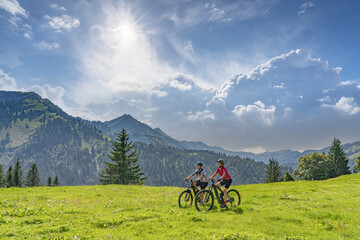 nice and remained young grandmother and her grandson riding their electrc mountain bikes in the...