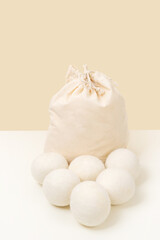 Obraz premium Wool Dryer Balls In Cotton Bag On Beige Background. Eco Friendly Laundry Supplies. Alternative Drying Of Linen. Still Life. Vertical Size