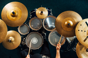 Drummer playing complete drum kit top view.