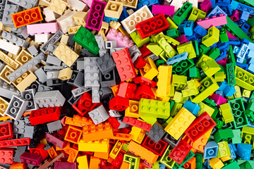 close-up of huge pile of stackable plastic toy bricks top view.  Colorful texture childhood education and development concept background.