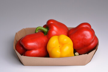 Red and yellow bell peppers in a paper container. Colorful red and yellow peppers paprika background. Eco-friendly packaging.