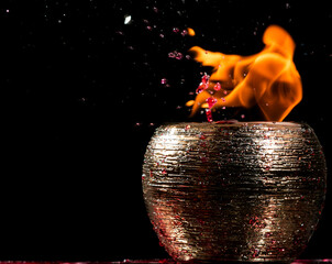 Pote dourado cheio com água misturada com fluido de isqueiro. Atando fogo e jogando uma pedra de gelo para causar um choque térmico.