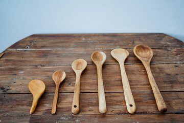 On the table are six wooden spoons of different sizes. There are six spoons in total.