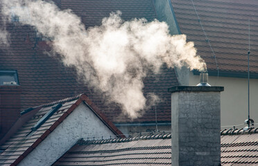 Smoke rising from the chimney in city - obrazy, fototapety, plakaty