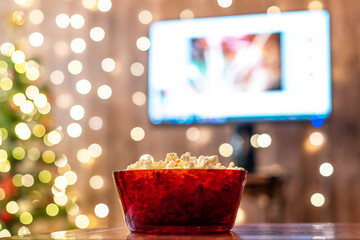 Christmas eve. Red bowl with popcorn on the table. Home cinema. Tv. Cropped, close up