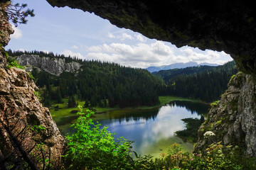 Fototapeta na wymiar view from a cave to a amazing blue mountain landscape with reflections