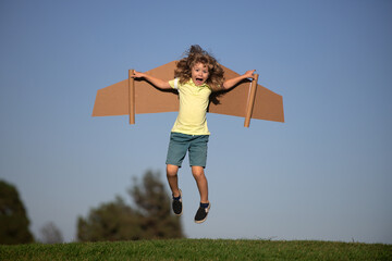 Child boy playing pilot on the sky blue background. Kid dreaming. Child playing with toy jetpack. Kid pilot having fun at park. Portrait of child against summer sky. Travel and freedom concept.