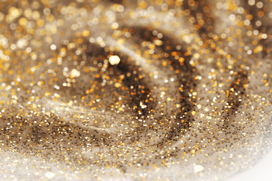 Shiny gold glittering background with soft selective focus. Nail polish texture.