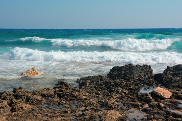 Powerful large sea waves hitting the rocky shore, on a sunny summer day