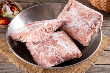Frozen ground meat, minced pork in a metal bowl. Ground chicken inclusive backs, necks, liver and heart. Frozen food. Concept for raw food diet for cats, dogs and pets.