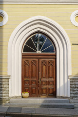 Wooden door over white stone arch and flower pot.