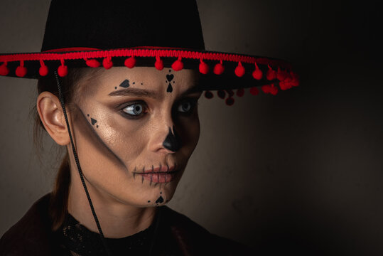 close-up portrait of Calavera Katrina. Skull makeup in a hat on a gray background looking away, serious look. Dia-de -los -muertos. Day of the Dead. Halloween.