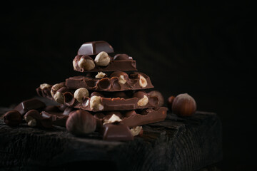 Pile of hazelnut milk chocolate and nuts on dark background