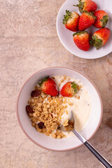 oatmeal muesli and strawberries in a round white plate on vintage paper background place for text