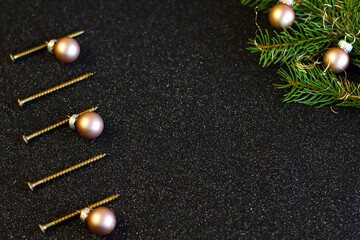 Christmas and New year tree of screws built of construction screws on black shiny background with golden balls, copy space