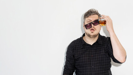 Party hangover. Alcohol problem. Drinking habit. After celebration. Messy man in sunglasses headache suffering with glass against head isolated on white empty space background.