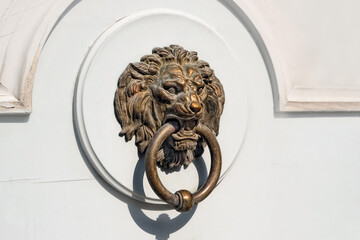Decorative door handle in form of lion head on white rustic wooden background. Door knocker with...