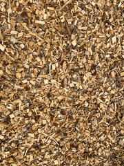 Wood chips on the ground makes a cool industrial pattern background. Yellow and brown colored. Vertical.