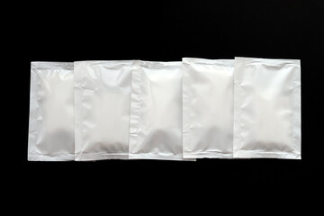 Blank white sachet packets stack mockup isolated on black background. Empty airtight pack mock-up for sauce, coffee, wet wipe, mayonnaise.