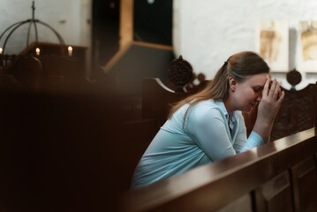 Woman is sitting in a church and praying.