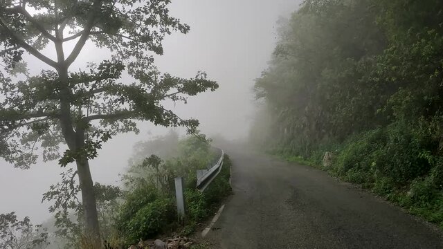 Movement in the fog. The rainy season in the Himalayas. Mountain road in steam clubs