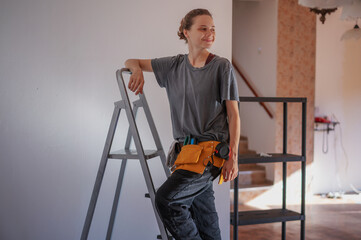 Beautiful young woman repairman standing on stepladder making repairs at home