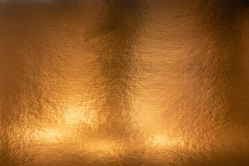 Textured metallic gold background with light and dark highlights, bright and shiny golden metal...