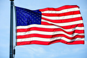 Sun shines through a U.S. flag at the Washington Monument on the National Mall in Washington, DC.
