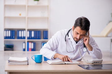 Young male doctor reading book in the clinic
