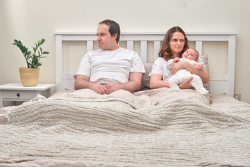 A father and mother quarrel with a baby boy, parents and an infante child on a home bed. The...