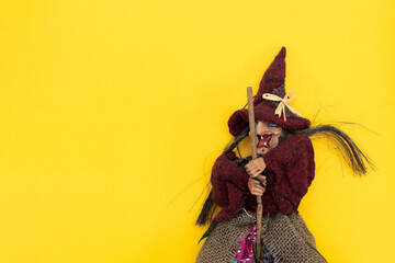 Halloween. Old Baba Yaga on a broomstick on a yellow background