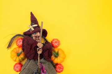Happy Halloween. Old Baba Yaga on a broomstick with pumpkins on a yellow background