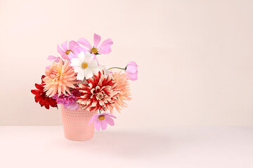 Dahlias and daisies in a vase on a light table.Autumn abstract composition, Thanksgiving day concept, seasonal background, banner or splash, greeting card or invitation