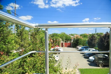 Fototapeta na wymiar Veranda and metal railing posts on the porch with view on parking