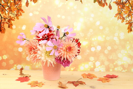 Autumn abstract composition with flowers of dahlias and daisies in a vase on blurred bokeh background, thanksgiving day concept, seasonal background, banner or splash, greeting card or invitation 