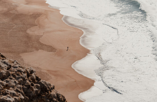 High Angle Shot Of A Person Alone On A Sandy Beach On A Sunny Day