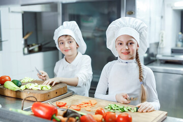 Children grind vegetables in the kitchen.