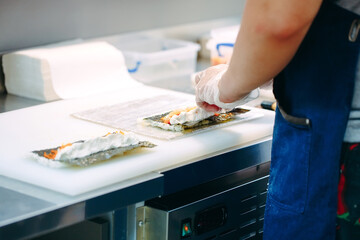Sushi delivery. Masked and gloved chefs prepare sushi In the Restaurant's kitchen.