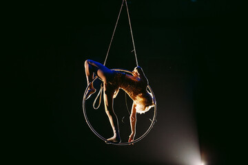 An aerial gymnast shows a performance in the circus arena.