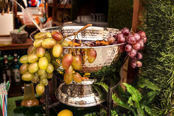 A bowl of mulled wine garnished with a bunch of grapes for a Mid-Autumn Festival. Delight with mulled wine at the autumn harvest festival. Outdoor food court at the festival
