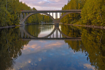Fototapeta na wymiar Finnish arched bridge with a narrow gauge railway, built in the early twentieth century, across the Yanisyoki River, Karelia, Russia. Autumn, september