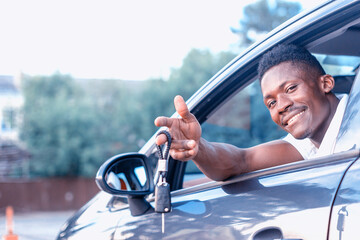 An African-American man holds a car key in his hands. Buying and renting a car