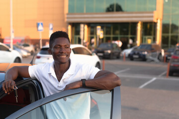 An African-American man holds a car key in his hands. Buying and renting a car