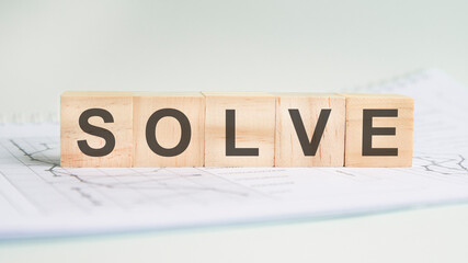 solve is written on light wooden blocks. the word is located on a sheet with charts and graphs