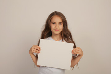 a beautiful sweet happy girl with long hair in a white T-shirt is holding a white sheet in her hands